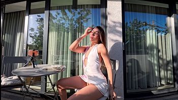 Wonderfully beautiful girl in a summer dress no panties on the balcony shows her tight shaved pussy to the neighbors